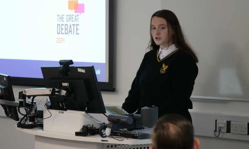 A female school pupil stood at the front of a classroom giving a speech 