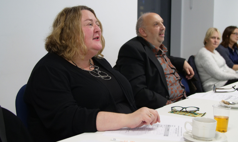 A woman and a man sat behind a table judging a debating competition 